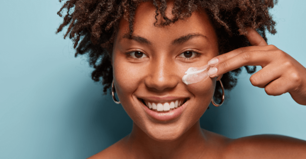Smiling woman applying face cream 