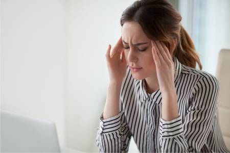 Person in pain from a migraine holding their head