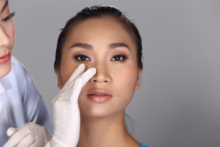 A plastic surgeon preparing a patient's wide nose for Botox injections