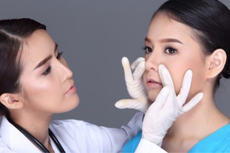 A plastic surgeon assessing the wide nose of a patient