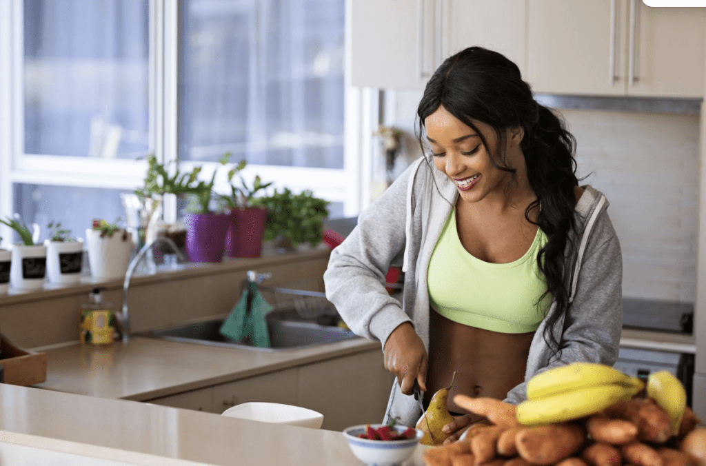 Girl cutting up fruit in kitchen after workout